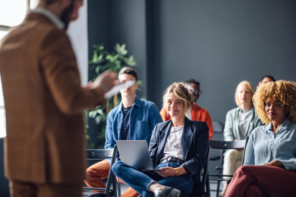 Focus on the audience whilst a man gives a meeting presentation 