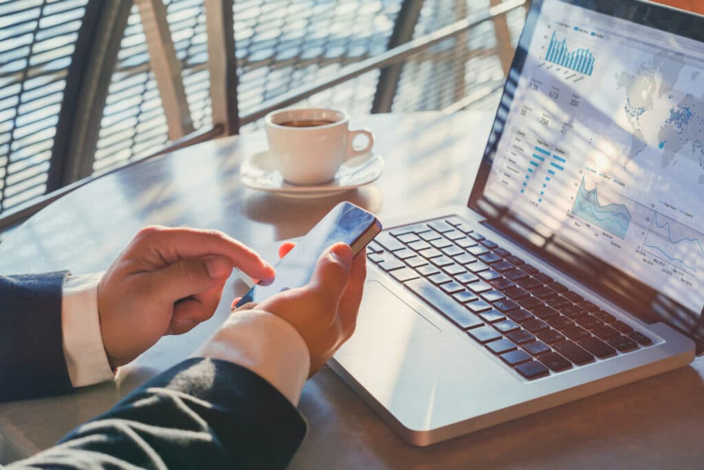 Photo of hands using a phone and laptop to conduct business