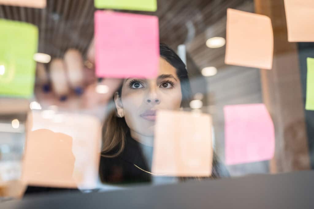 Young woman writing in post it at the office