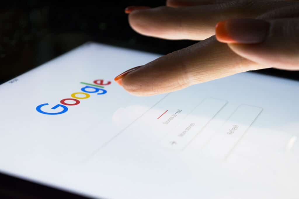 A woman's hand is touching screen on tablet computer iPad Pro at night for searching on Google search engine. Google is the most popular Internet search engine in the world. Photo taken at company office.