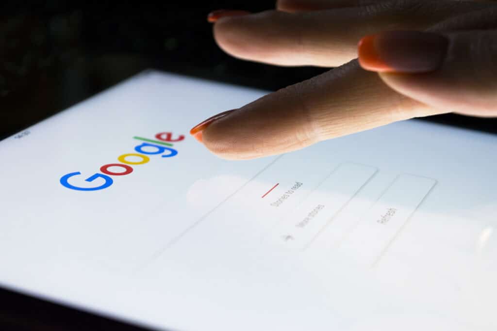 A woman's hand is touching screen on tablet computer iPad Pro at night for searching on Google search engine.